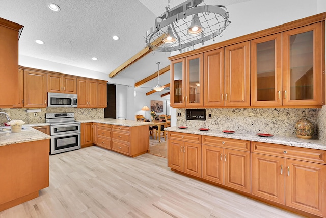 kitchen with pendant lighting, appliances with stainless steel finishes, backsplash, vaulted ceiling, and ceiling fan