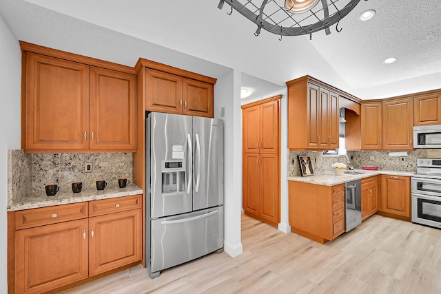 kitchen featuring vaulted ceiling, appliances with stainless steel finishes, backsplash, and sink