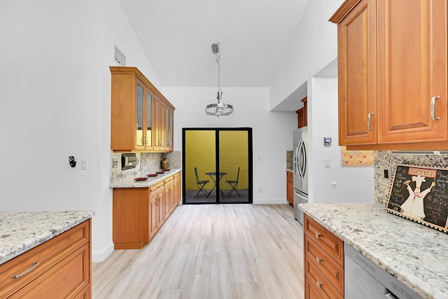 kitchen with pendant lighting, appliances with stainless steel finishes, glass insert cabinets, and light stone countertops