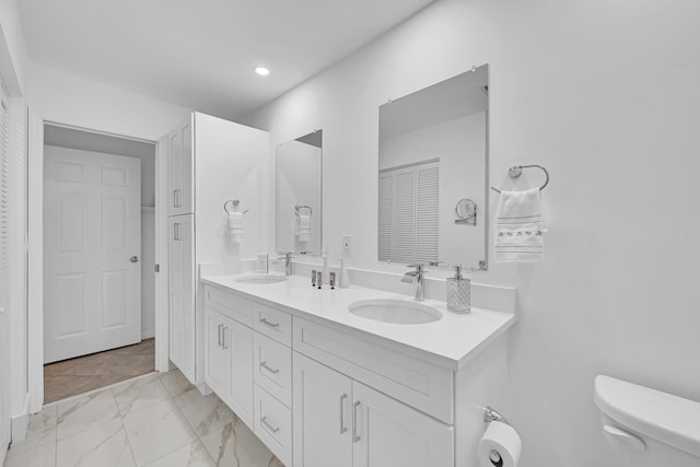 bathroom featuring marble finish floor, double vanity, a closet, and a sink