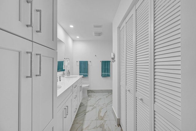 bathroom featuring a sink, baseboards, marble finish floor, a closet, and double vanity