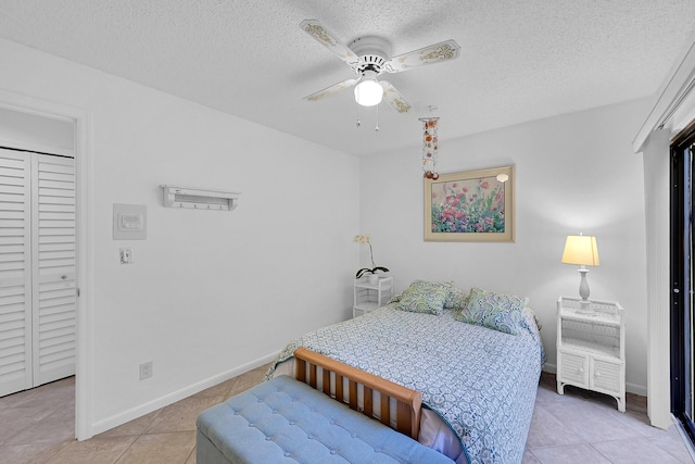 bedroom with ceiling fan, light tile patterned floors, and a textured ceiling