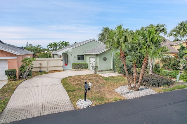 single story home featuring decorative driveway, fence, and stucco siding