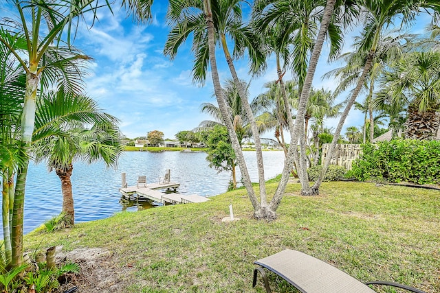 view of yard with a dock, a water view, and fence