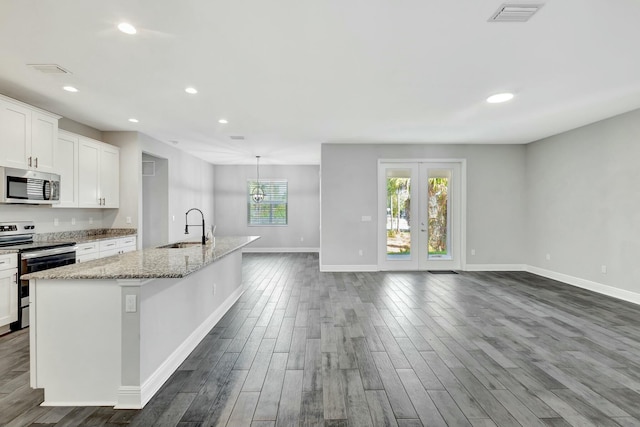 kitchen featuring sink, a center island with sink, appliances with stainless steel finishes, light stone countertops, and white cabinets