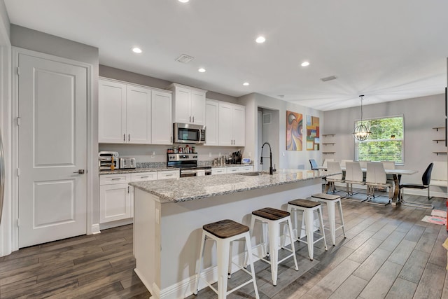 kitchen featuring a center island with sink, appliances with stainless steel finishes, dark wood-type flooring, and white cabinets