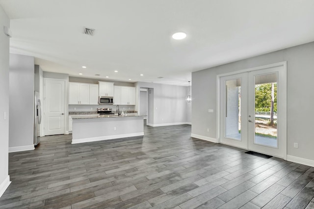 kitchen with white cabinetry, dark hardwood / wood-style floors, an island with sink, and appliances with stainless steel finishes