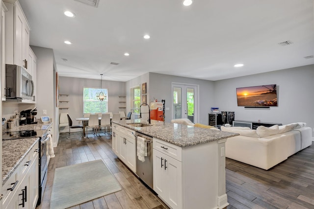 kitchen with dark hardwood / wood-style floors, an island with sink, sink, white cabinetry, and appliances with stainless steel finishes