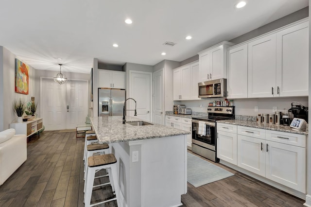 kitchen with sink, appliances with stainless steel finishes, dark wood-type flooring, and a kitchen island with sink