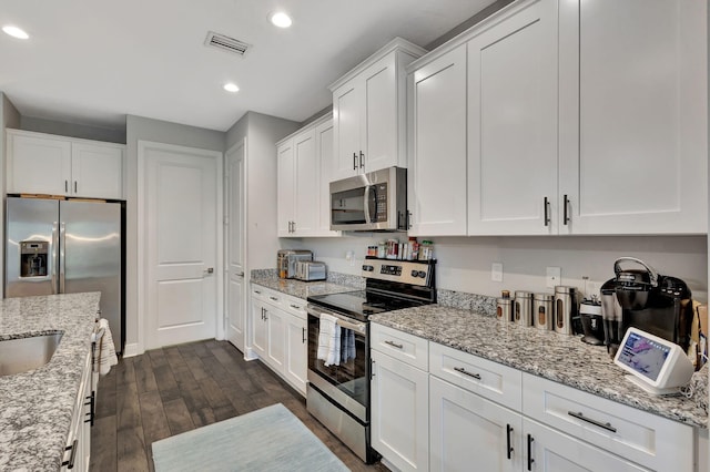 kitchen featuring appliances with stainless steel finishes, white cabinetry, light stone countertops, and dark wood-type flooring