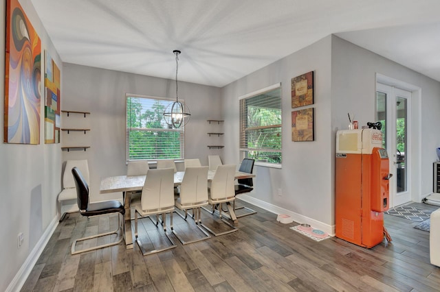 dining space with wood-type flooring and an inviting chandelier