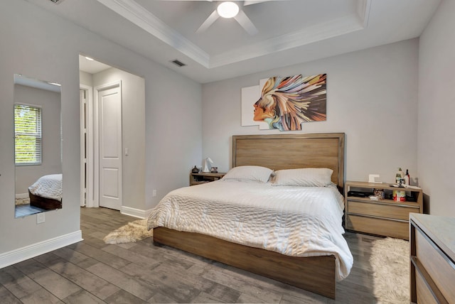 bedroom featuring ceiling fan, ornamental molding, a tray ceiling, and dark hardwood / wood-style floors