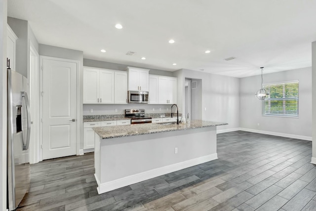 kitchen featuring sink, white cabinetry, decorative light fixtures, appliances with stainless steel finishes, and a kitchen island with sink