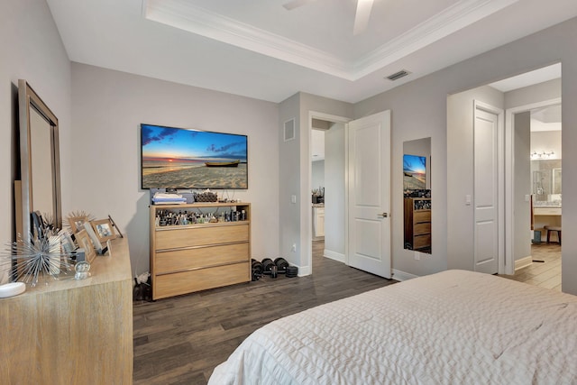 bedroom with dark hardwood / wood-style flooring, ensuite bath, a raised ceiling, and ceiling fan