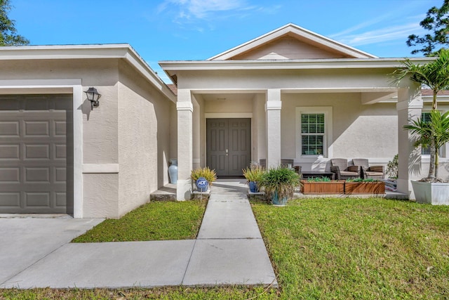 view of exterior entry featuring a garage, a yard, and covered porch