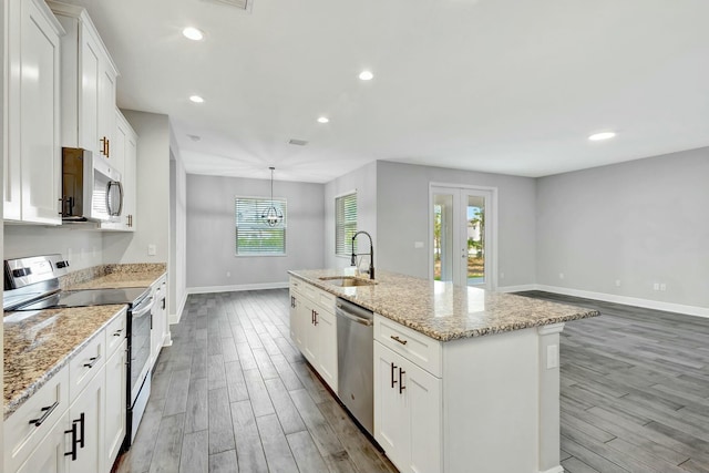 kitchen with sink, decorative light fixtures, an island with sink, stainless steel appliances, and white cabinets