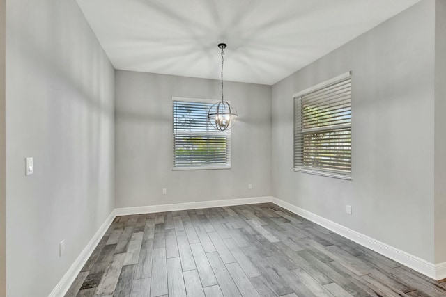 unfurnished room featuring a notable chandelier and hardwood / wood-style flooring