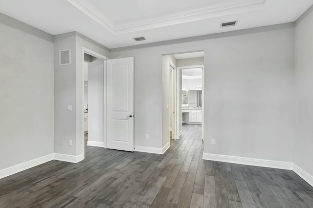 spare room with a raised ceiling, ornamental molding, and dark hardwood / wood-style flooring