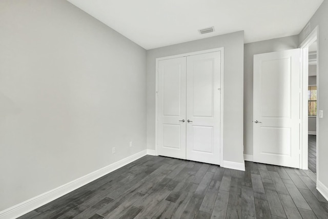 unfurnished bedroom featuring dark wood-type flooring and a closet