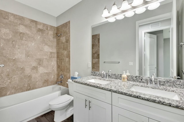 full bathroom with tiled shower / bath, hardwood / wood-style floors, vanity, and toilet