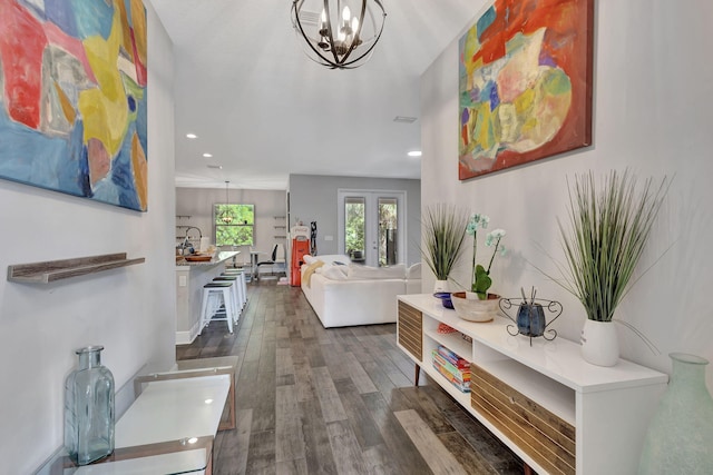 hallway with an inviting chandelier, french doors, and dark wood-type flooring