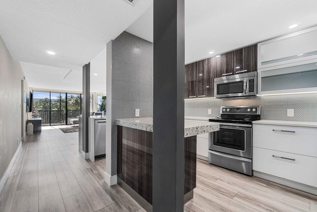 kitchen with white cabinets, appliances with stainless steel finishes, light hardwood / wood-style flooring, and dark brown cabinetry