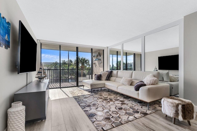 living room featuring light hardwood / wood-style floors, a wall of windows, and a textured ceiling