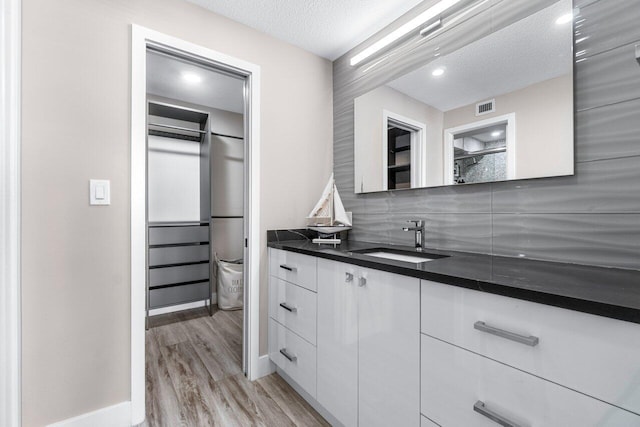 kitchen with light hardwood / wood-style flooring, white cabinets, sink, and a textured ceiling