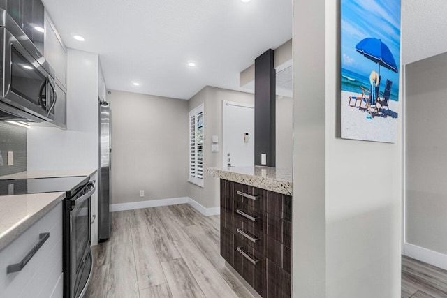 kitchen featuring dark brown cabinetry, stainless steel appliances, and light hardwood / wood-style floors