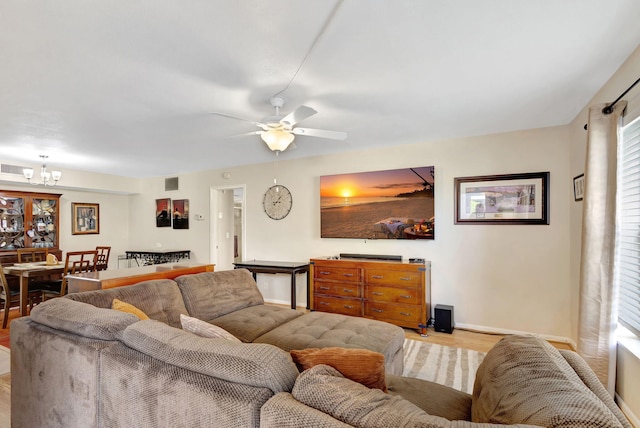 living room with light hardwood / wood-style floors and ceiling fan with notable chandelier