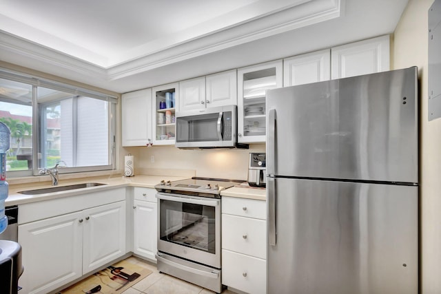 kitchen featuring sink, a tray ceiling, white cabinetry, stainless steel appliances, and light tile patterned floors