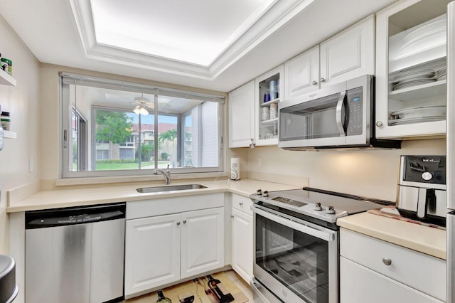 kitchen with appliances with stainless steel finishes, sink, a raised ceiling, ceiling fan, and white cabinets