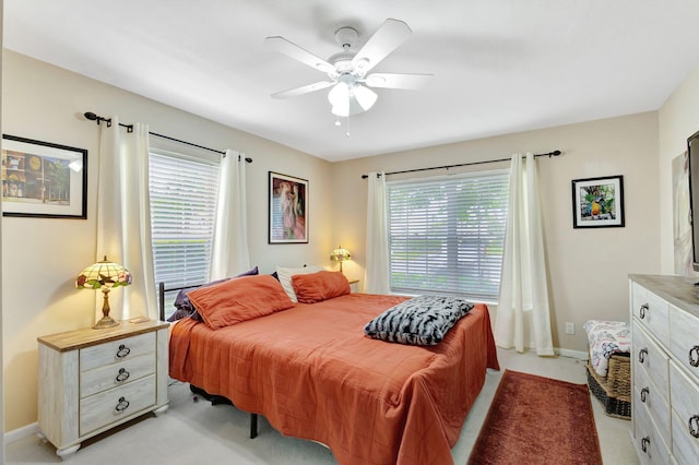 carpeted bedroom featuring multiple windows and ceiling fan