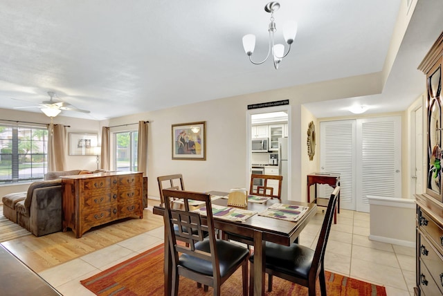 dining room with light hardwood / wood-style floors and ceiling fan with notable chandelier