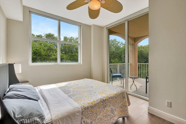 bedroom with expansive windows, access to outside, hardwood / wood-style floors, and ceiling fan