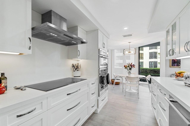 kitchen featuring white cabinetry, wall chimney range hood, and black electric cooktop