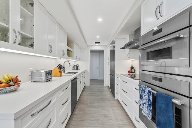 kitchen with white cabinetry, wall chimney range hood, black appliances, and sink