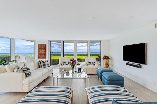 living room featuring expansive windows, a water view, and light hardwood / wood-style floors