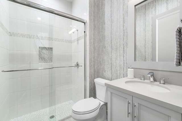 bathroom with a shower with door, vanity, and toilet