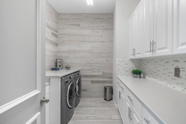 washroom with light hardwood / wood-style flooring, separate washer and dryer, and cabinets