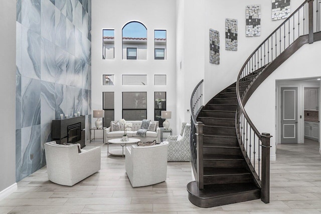 living room with a towering ceiling, light hardwood / wood-style flooring, and tile walls