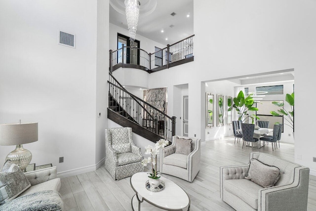 living room featuring light hardwood / wood-style floors, an inviting chandelier, and a high ceiling