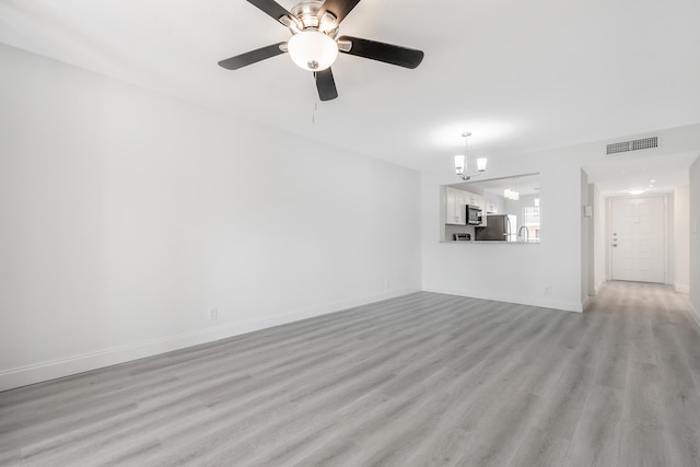 unfurnished living room featuring ceiling fan with notable chandelier and light hardwood / wood-style flooring