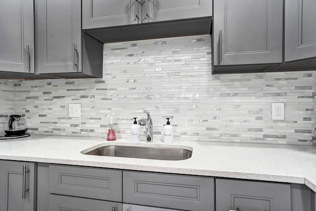 kitchen with gray cabinetry, sink, and tasteful backsplash