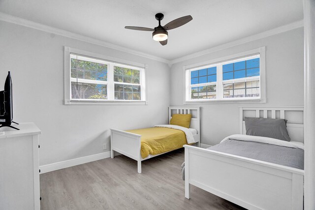 bedroom with light hardwood / wood-style floors, ornamental molding, and ceiling fan