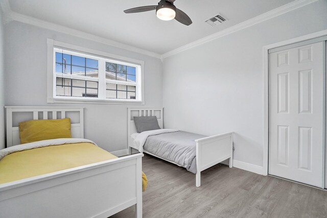 bedroom with crown molding, light hardwood / wood-style floors, and ceiling fan