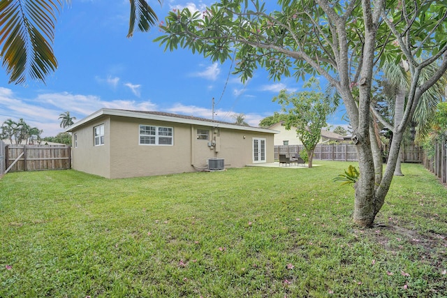 rear view of property featuring french doors, a lawn, and central air condition unit