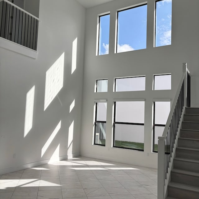 unfurnished living room featuring light tile patterned flooring and a high ceiling