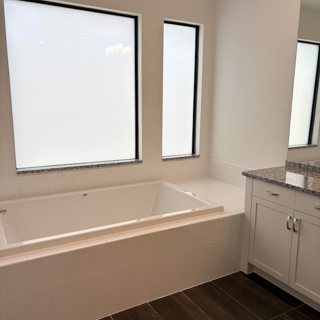 bathroom with vanity, a relaxing tiled tub, and hardwood / wood-style floors