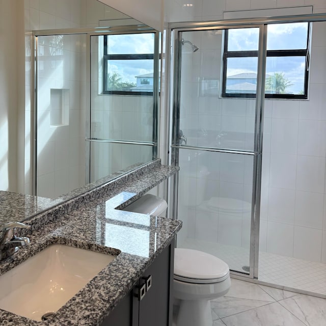 bathroom featuring vanity, toilet, a healthy amount of sunlight, and a shower with door